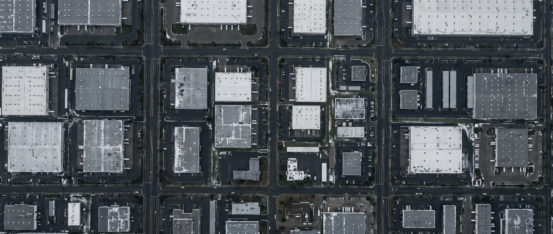 Top-down aerial view of commercial flat roofs tracked for verified storm and hail damage