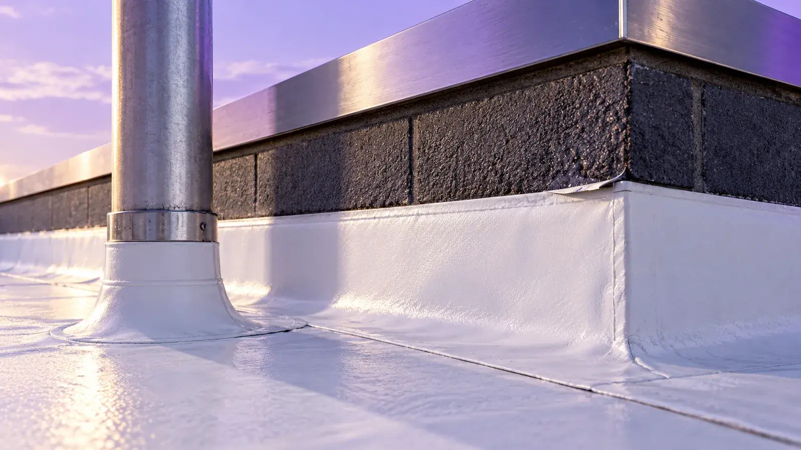 A close view of commercial roof flashing at a parapet and pipe penetration.