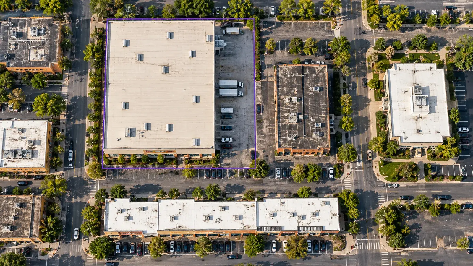 Overhead view of a commercial district with one warehouse parcel outlined in violet for further research.
